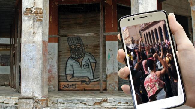 Un celular ante un grafiti en La Habana.