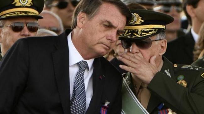 El mandatario brasileño Jair Bolsonaro conversa con un militar.