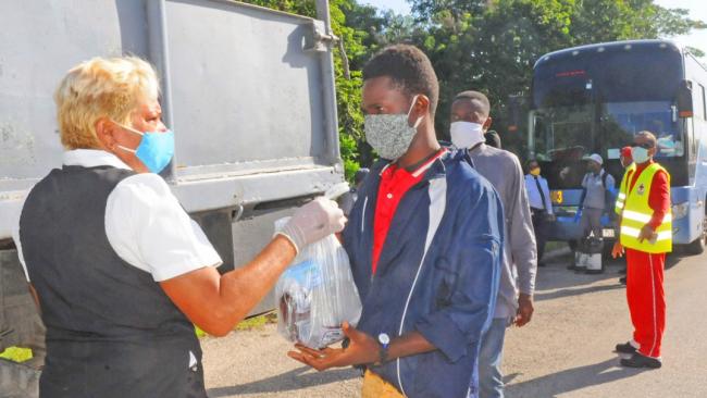 Una funcionaria cubana entrega una bolsa a un haitiano repatriado.