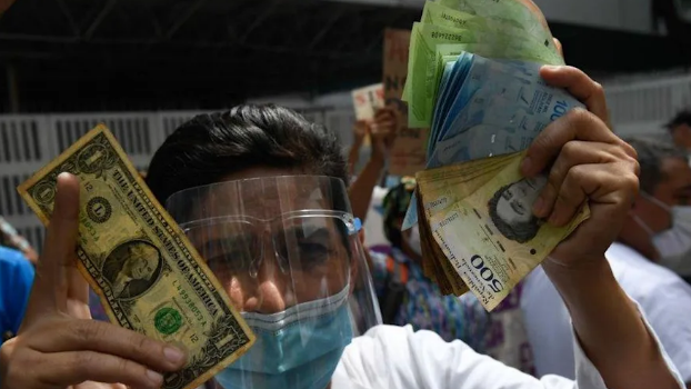 Un venezolano muestra la cantidad de bolívares necesarios para comprar un dólar.