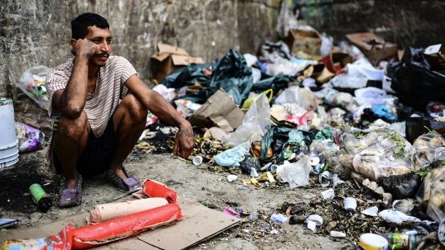 Un venezolano rodeado de basura.