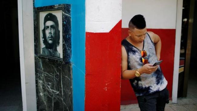 Un joven cubano revisa su teléfono.