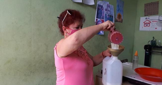 Venta de leche racionada a granel en una bodega en Matanzas.