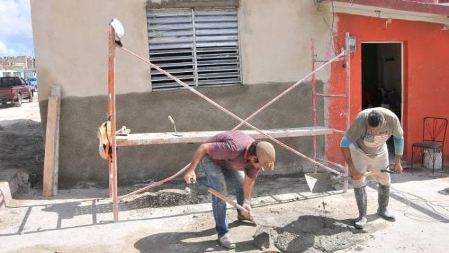 Dos cubanos trabajan en la construcción de una vivienda.