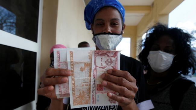 Una mujer muestra billetes de pesos cubanos.