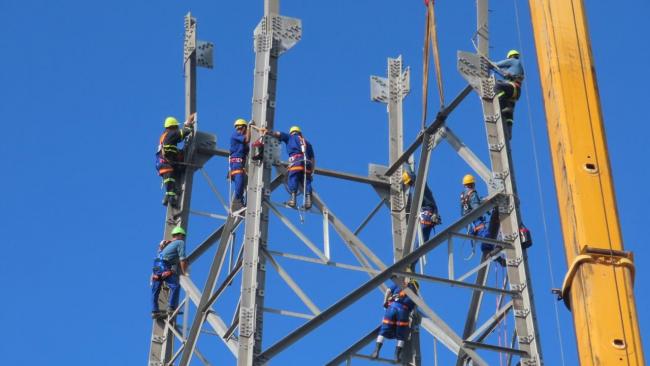 Trabajadores eléctricos cubanos en el montaje de una estructura.