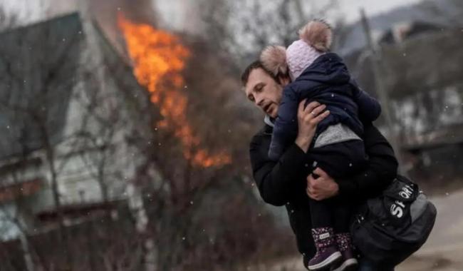 n hombre y un bebé escapan de los bombardeos en la localidad de Irpín, cercana a Kiev, Ucrania.