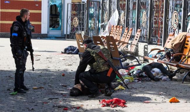 Militares ucranianos junto al cadáver de una mujer tras el bombardeo a la estación de Kramatorsk.
