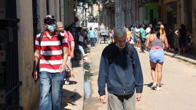 Un anciano cubano con rostro de cansancio en una calle de La Habana junto a otros transeúntes.
