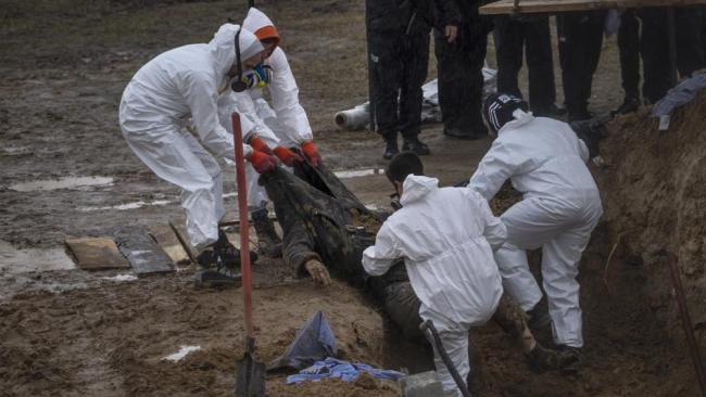 Trabajadores del cementerio retiran un cuerpo de una fosa común para identificarlo en una morgue, en Bucha, en las afueras de Kiev, 10 de abril.