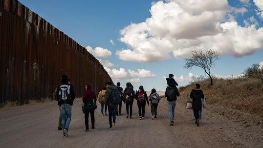 Migrantes caminan por la frontera entre México y EEUU.