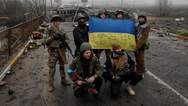 Soldados de Ucrania posan con una bandera.