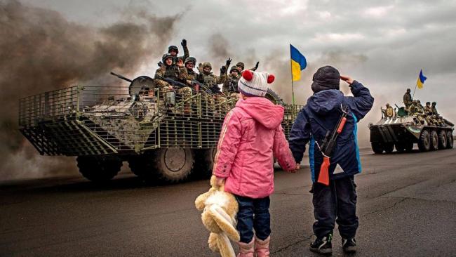 Niños ucranianos saludan a tropas de su país.