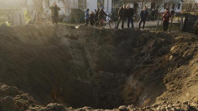 Personas miran el cráter de una explosión en un pueblo de Horodnya, región de Chernigov, Ucrania, el jueves 14 de abril de 2022.