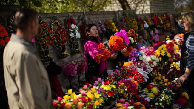 Victoria Kardeldevska en su puesto de flores en el cementerio de Kapustyanyy durante el día que los ucranianos marcan como el día de los muertos, en Zaporizhzhia, Ucrania, 1 de mayo.