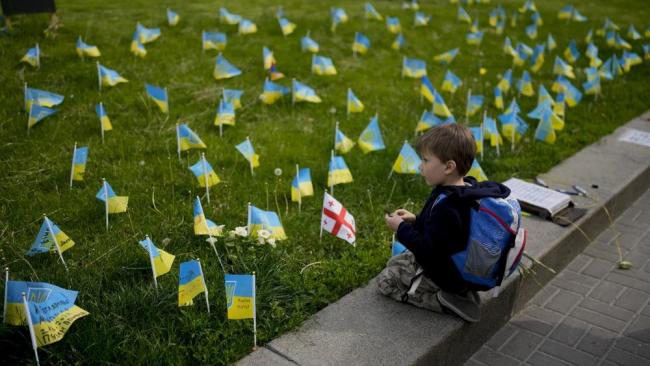 Un niño mira banderas en honor a soldados muertos en la guerra contra Rusia en el centro de Kiev, Ucrania, el lunes 23 de mayo de 2022.