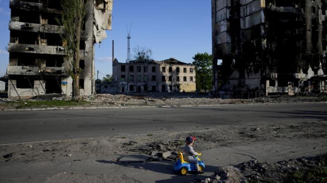 Un niño juega frente a las casas destruidas por los bombardeos en Borodyanka, Ucrania, el martes 24 de mayo de 2022.