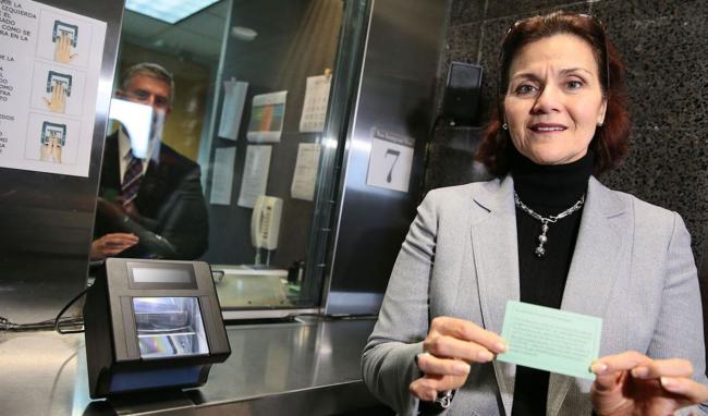 Una mujer sostiene su documento migratorio para entrar a EEUU.