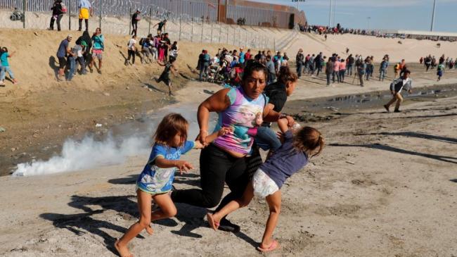 Migrantes huyen de los gases lacrimógenos lanzados desde la frontera entre Estados Unidos y México en Tijuana.