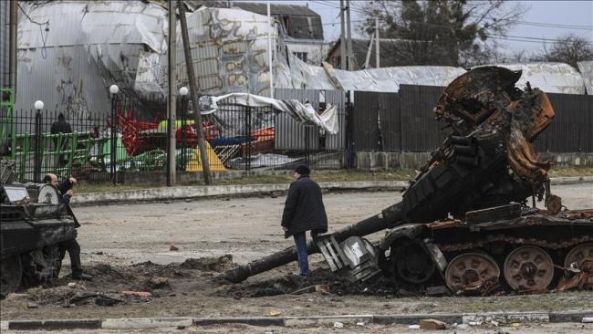 Dos personas se hacen fotos frente a un tanque de guerra destruido en Ucrania. 