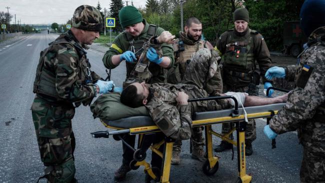 Miembros de la unidad móvil de evacuación del ejército ucraniano atienden a un soldado herido antes de su traslado a un hospital en ambulancia.