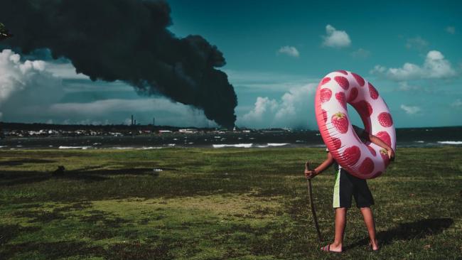 Un niño observa la columna de humo de la Base de Supertanqueros de Matanzas en llamas.