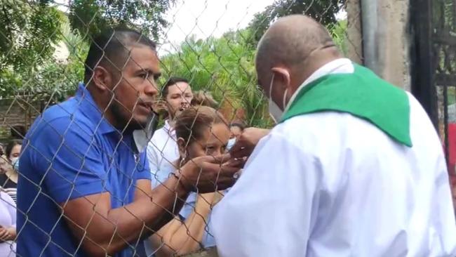 El sacerdote Sebastián López atiende a los fieles a través de una cerca que separa el templo de la calle.