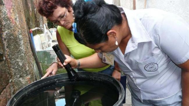 Una inspectora revisa un depósito de agua en una vivienda en Cuba.