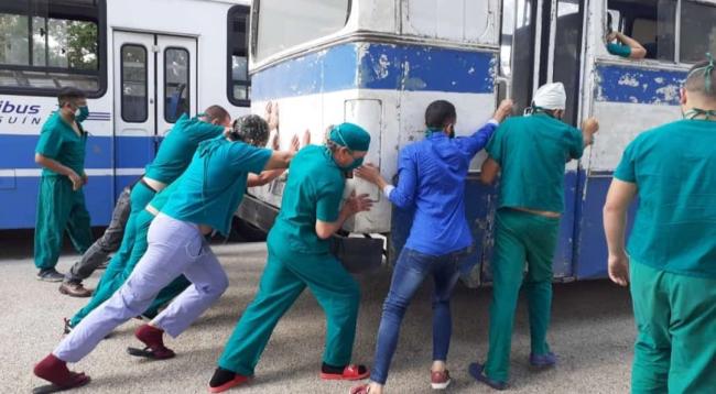 Trabajadores de un hospital de Holguín empujan una guagua para intentar que arranque.