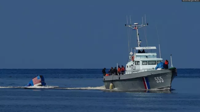 Barco de las Traopas Guardafronteras de Cuba remolca a la embarcación de balseros interceptada.