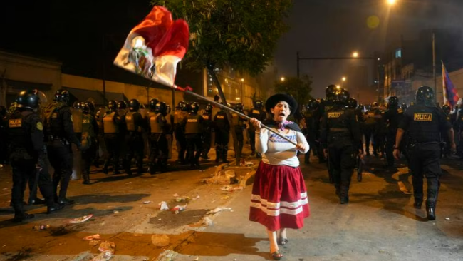 Una mujer se manifiesta entre tropas antimotines en Perú.