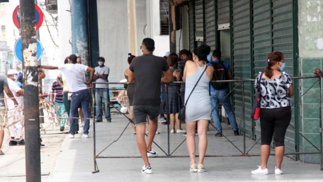 Hombres y mujeres en una cola en La Habana.
