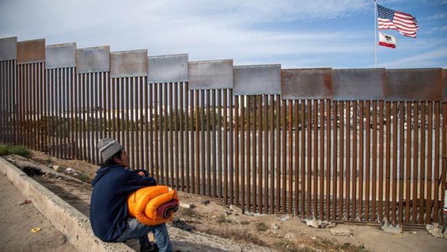 Un migrante ante el muro que divide a EEUU se México.