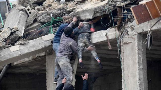 Varias personas rescatan este lunes a una niña atrapada en los escombros de un edificio en Jandaris, en el noroeste de Siria, una zona controlada por los rebeldes.
