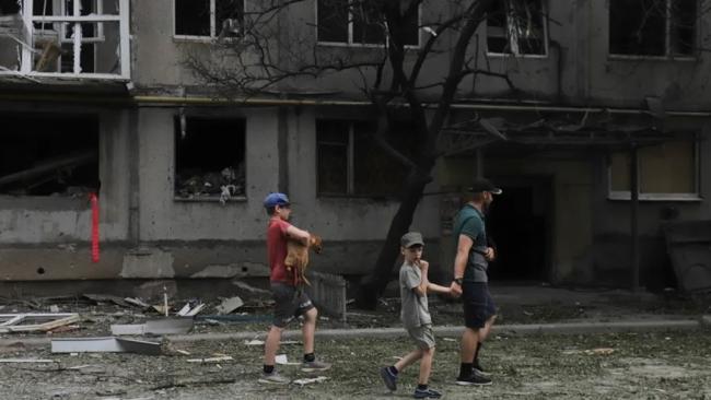 Personas en una calle de Bajmut, en la región de Donetsk, en la que se aprecian los efectos de los bombardeos rusos. 