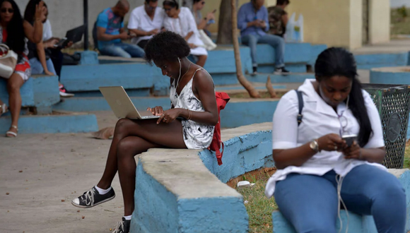 Cubanos se conectan a internet en una wifi pública en un parque.