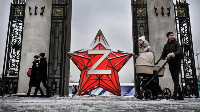 Moscovitas pasean frente a una decoración celebratoria de la invasión de Ucrania a la entrada del Parque Gorki.