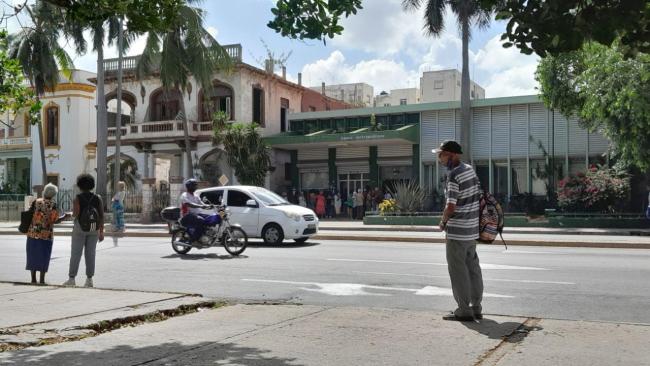 Un banco en La Habana con personas haciendo cola.