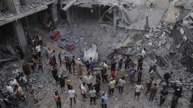 Palestinos buscan cadáveres y supervivientes entre los escombros de un edificio residencial derribado por un ataque aéreo israelí, en el campo de refugiados de Jan Yunis, en el sur de la Franja de Gaza, este 19 de octubre. 