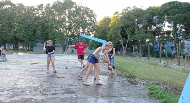 Estudiantes de la Universidad de Matanzas limpiando una cancha de baloncesto inundada por un salidero.