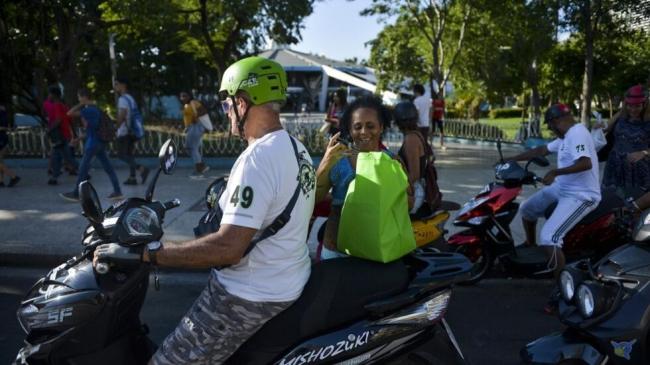 Cubanos en motos eléctricas en La Habana.