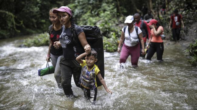 Migrantes vadean un río en el Tapón del Darién, mayo de 2023.