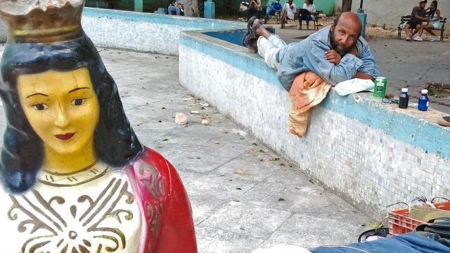 Un cubano junto a una figura religiosa en La Habana.