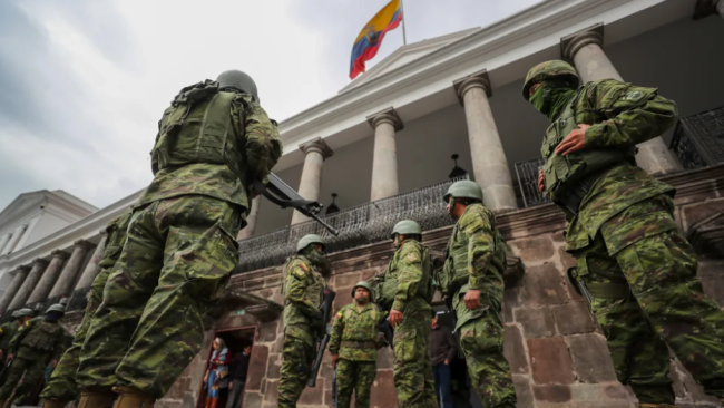 Militares en traje de campaña ante un edificio público en Ecuador.