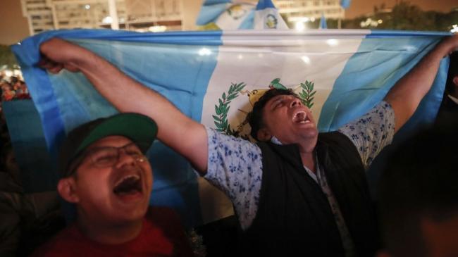 Personas reaccionan a la transmisión de la posesión del nuevo presidente de Guatemala, Bernardo Arévalo.