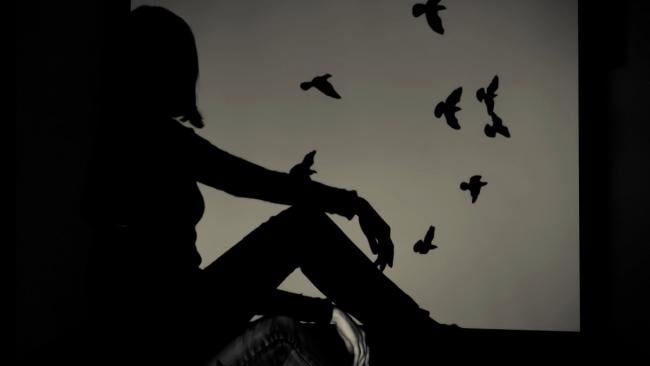 Mujer mirando el vuelo de unos pájaros.