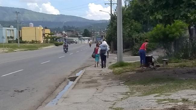 Una mujer cocina con leña junto a una carretera en Santiago de Cuba.