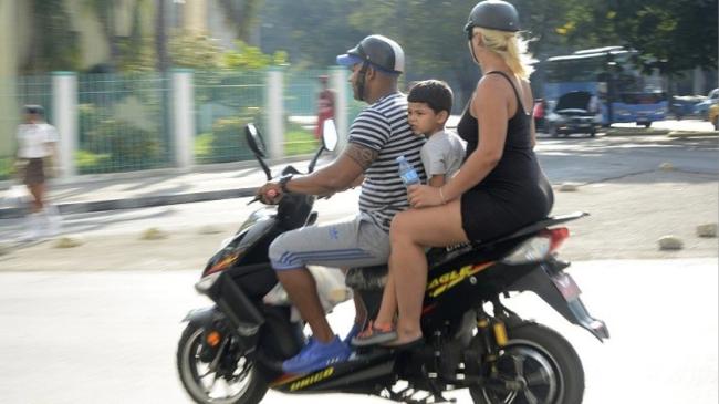 Cubanos en una moto eléctrica.