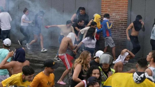 Opositores al Gobierno de Nicolás Maduro corren para protegerse de los gases lacrimógenos durante una protesta en el barrio de Catia, Caracas.