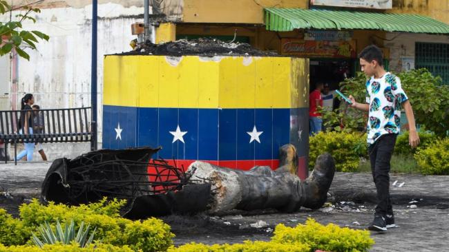 Una estatua destruida de Hugo Chávez yace junto a su base en Valencia, Venezuela.